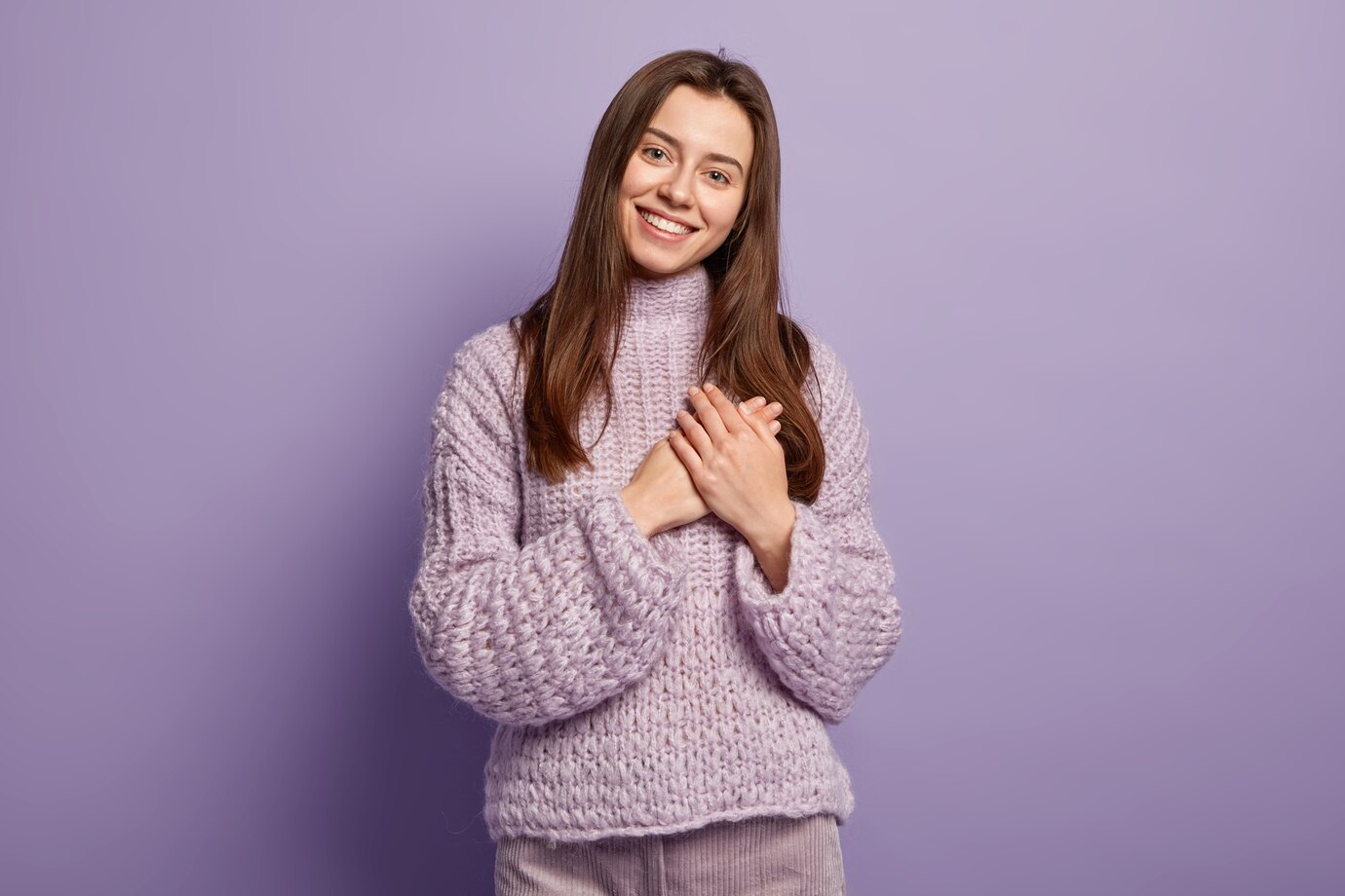 portrait-happy-young-european-woman-keeps-hands-breast-shows-heart-gesture-expresses-gratitude-being-thankful-models-against-purple-wall-body-language-monochrome-people-devotion_273609-26597